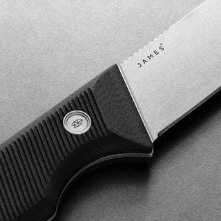 Close-up of James The Humboldt Knife featuring textured black G10 handle with logo and Böhler N690 steel blade
