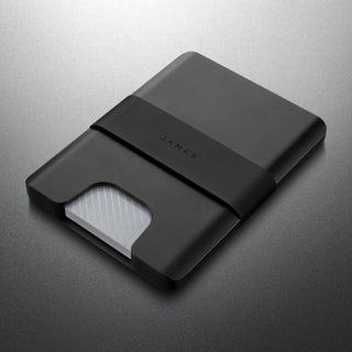 James The Lowe Wallet in black aluminum with silicone band and visible card edge on gray background