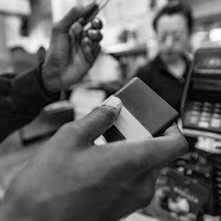 James The Lowe Wallet held in hand near a payment terminal, showcasing compact aluminum and silicone design