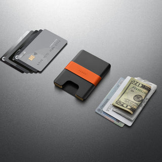 James The Lowe Wallet in black aluminum with orange silicone band shown with cards and cash