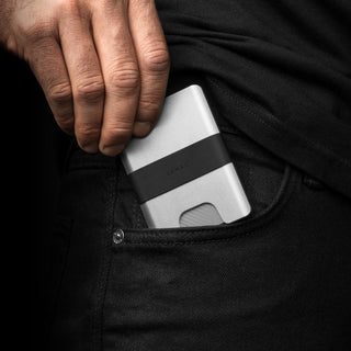 James The Lowe Wallet in silver aluminum with black silicone band being placed in back pocket