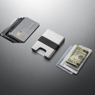 James The Lowe Wallet aluminum body with silicone band holding cards and cash on gray surface