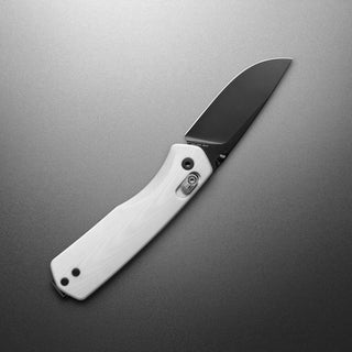 James The Carter Knife with white Micarta handle and black VG-10 blade angled on gray surface by The James Brand