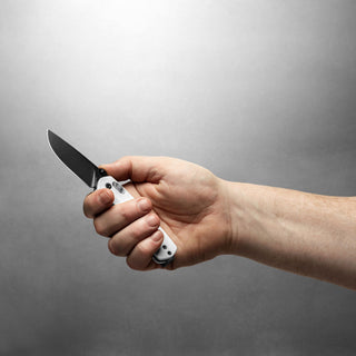 James The Carter Knife by The James Brand held open with white G10 handle visible against gray background