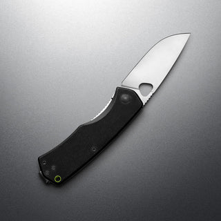 James The Folsom Knife with black G10 handle and VG-10 steel blade partially open on gray surface