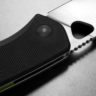 Close-up of James The Folsom Knife handle showing textured black G10 with liner lock and partial serrated blade