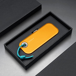 James The Palmer Knife in anodized orange aluminum with teal lanyard, displayed in a black gift box by The James Brand