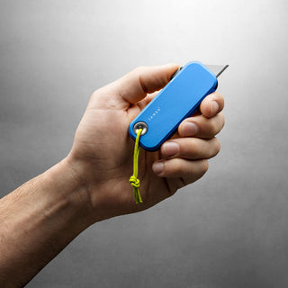 Hand holding James The Palmer Knife with blue anodized aluminum handle and green lanyard rope