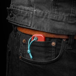 James The Palmer Knife with red anodized aluminum handle and blue lanyard in black jeans pocket
