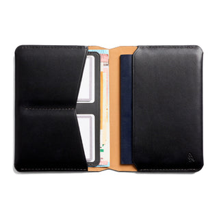 Bellroy Passport Cover open showing black leather exterior and tan leather interior with card slots and compartments