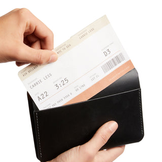 Bellroy Passport Cover in black leather holding a boarding pass with visible stitching detail
