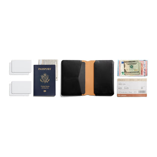 Bellroy Passport Cover open flat showing black leather exterior and tan interior with passport and cards nearby