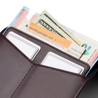 Bellroy Passport Cover in dark brown leather holding travel documents and currency bills inside pockets