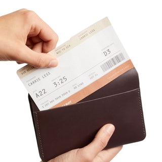 Bellroy Passport Cover in dark brown leather held open revealing a flight boarding pass inside