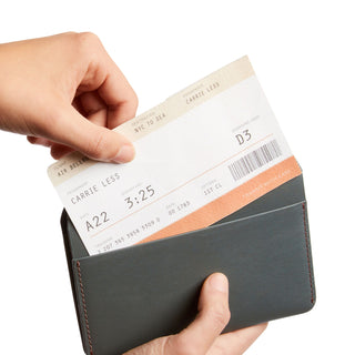Bellroy Passport Cover in dark leather held open with boarding pass inside, showing smooth texture and stitching