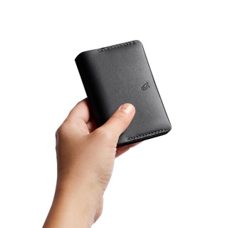 Hand holding black leather Bellroy Under Cover card holder with smooth texture and embossed logo