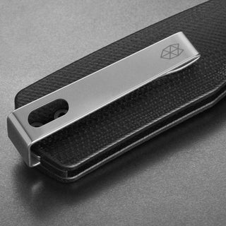 Close-up of James The Carter Knife showing black Micarta handle with polished silver clip and geometric logo