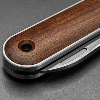 Close-up of James The Wayland Knife handle showcasing smooth rosewood and metal frame details