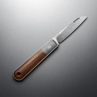 James The Wayland Knife with rosewood handle and patterned steel blade on gray background