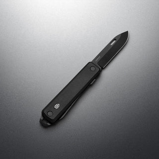 James The Ellis Scissors Knife with black textured handle and sharp matte black blade on gray surface