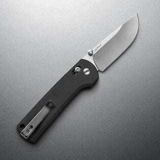 James The Kline Knife with black Micarta handle and polished drop point blade open on gray surface