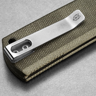 Close-up of James The Kline Knife’s textured Micarta handle with silver metal clip and logo engraving
