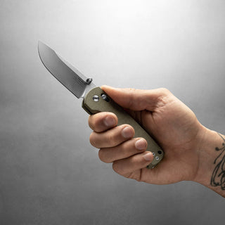 Hand holding James The Kline Knife with green Micarta handle and open drop point blade