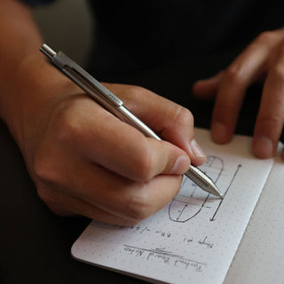 James The Burwell Ballpoint Pen in stainless steel used to write in a notebook