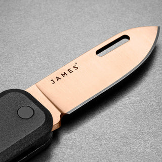 James The Elko Knife with sleek titanium blade and black textured handle close-up view