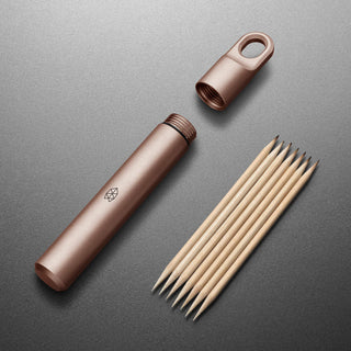 James The Randolph Capsule titanium container with water-resistant seal and wooden toothpicks beside it on gray surface