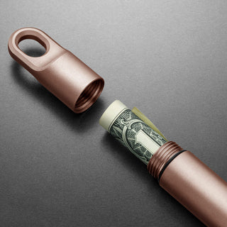 James The Randolph Capsule in rose titanium with rolled dollar bill inside, showing threaded opening and rubber seal ring