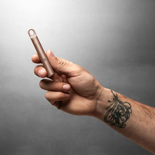 Hand holding James The Randolph Capsule in bronze titanium with matte finish and loop top design
