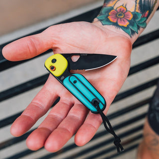James The Redstone Knife held in hand showing black blade with yellow and turquoise polypropylene handle
