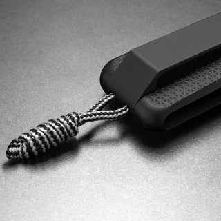 Close-up of James The Barnes Knife handle showing textured grip and braided lanyard by The James Brand