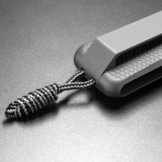 James The Barnes Knife with textured titanium handle and black-and-white woven lanyard detail close-up