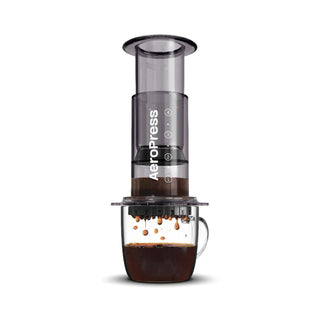 AeroPress Clear Coffee Maker brewing dark coffee into a glass cup with visible dripping grounds
