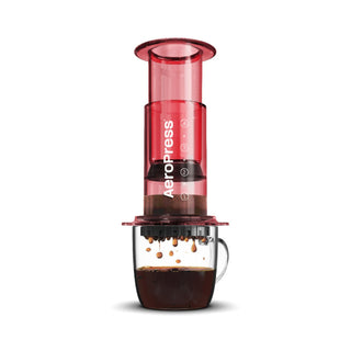 AeroPress Clear Coffee Maker brewing fresh coffee with red translucent plastic chamber over glass cup