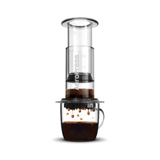 AeroPress Clear Coffee Maker brewing fresh coffee with dark liquid dripping into glass cup below