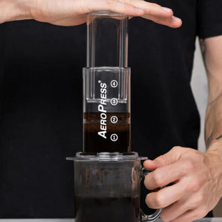 AeroPress Clear Coffee Maker brewing coffee with visible coffee grounds and water markings in use