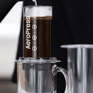 AeroPress Clear Coffee Maker brewing coffee with visible measurement markings and clear plastic body