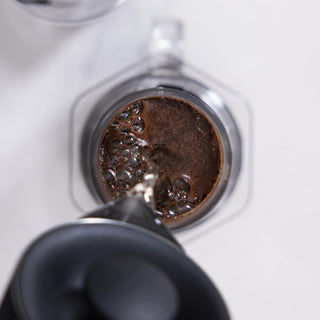 AeroPress Clear Coffee Maker brewing coffee with dark coffee grounds and bubbles visible inside