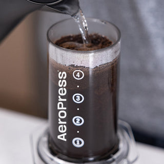 AeroPress Clear Coffee Maker brewing fresh coffee with water being poured over grounds inside the clear chamber