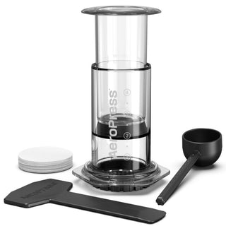 AeroPress Clear Coffee Maker with plunger, scoop, filter papers, and stirrer displayed on white background