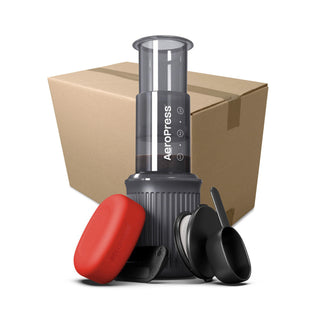 AeroPress Go Coffee Maker with black brewing chamber, red case, measuring scoop, and cardboard box background