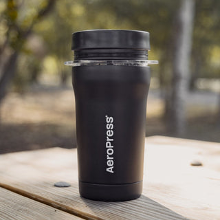 AeroPress Go Plus Travel System portable black coffee maker with matte finish on wooden table outdoors