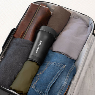 AeroPress Go Plus Travel System in black stainless steel placed in packed suitcase with clothes and pouch