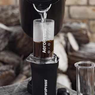 AeroPress Go Plus Travel System brewing fresh coffee with clear plastic chamber and black base outdoors