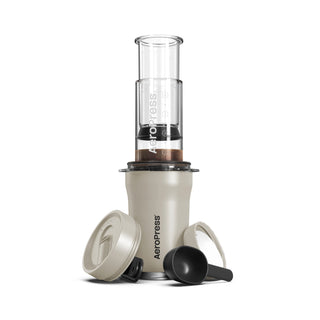 AeroPress Go Plus Travel System in beige with clear brewing chamber and black scoop on white background