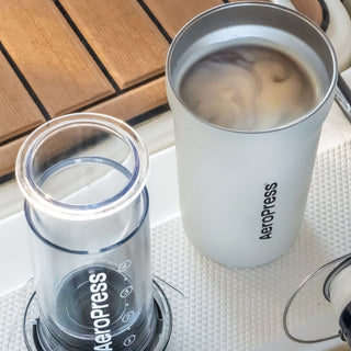 AeroPress Go Plus Travel System showing transparent brewing chamber and filled stainless steel cup on kitchen surface