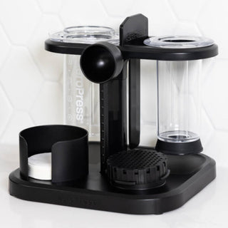 AeroPress Organizer in black plastic holding filters, scoops, and clear AeroPress coffee makers upright